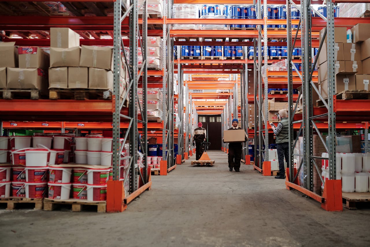 Offerings Warehouse interior showing workers handling boxes and organized shelves filled with products.