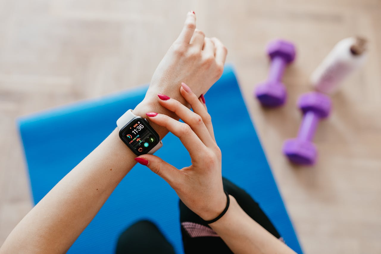 About A woman checks fitness data on her smartwatch during a workout at home.